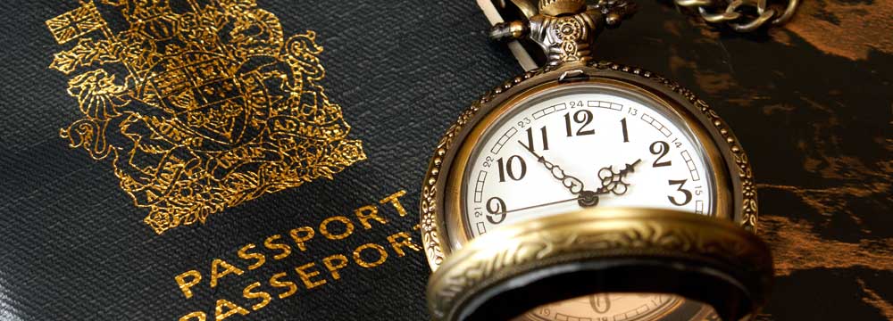 A vintage pocket watch resting on a passport.