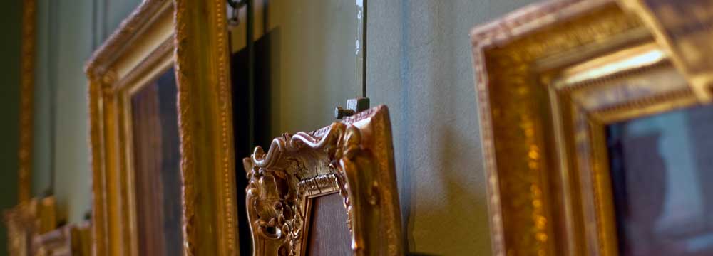A close-up of an ornate golden picture frame hanging on a wall.