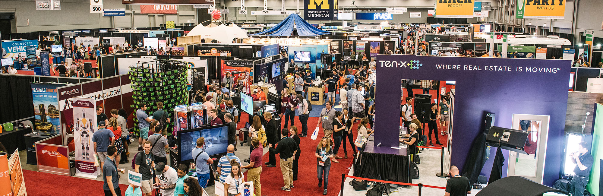Busy convention floor with numerous booths and attendees.
